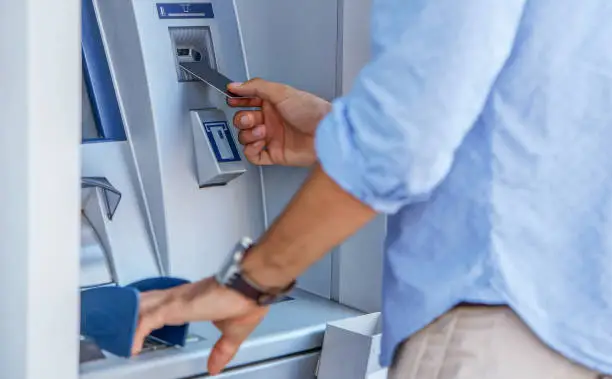 Man using a street ATM machine and withdrawing money, close up photo