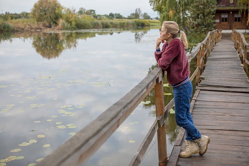 beautiful girl look dreaming  stands on a wooden bridge.