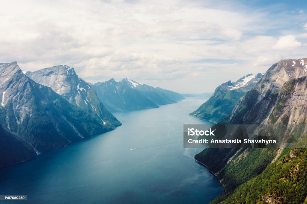 Dramatic Aerial View of Hjorundfjord in Summer Colours in Norway Drone high-angle photo of majestic fjord surrounded by beautiful snowcapped mountain peaks in Western Norway, Scandinavia On Top Of Stock Photo