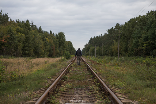 Man walk away on railroad with warm light. Traveler guy on railroad.