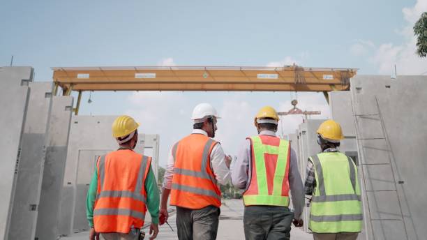 team di appaltatori in uniforme di sicurezza che lavorano nel settore immobiliare. ingegnere civile professionista o architetto edile discutendo con il caposquadra sulla produzione di pareti prefabbricate di complessi residenziali in fabbrica. concetto di  - construction building contractor housing development house foto e immagini stock