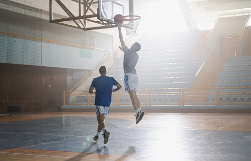 Two professional basketball players playing one on one on the floor of a indoor basketball court.