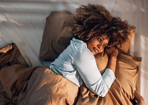 A smiling African-American female waking up in the morning.
