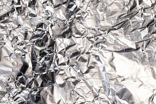 old used crumpled aluminum foil , close-up of a foil structure with crumbs from food