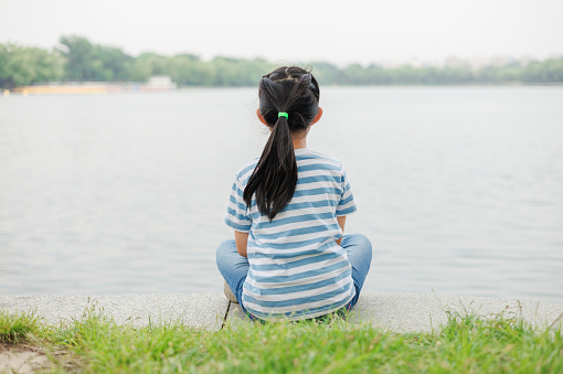 Little Girl Sitting by the Lake