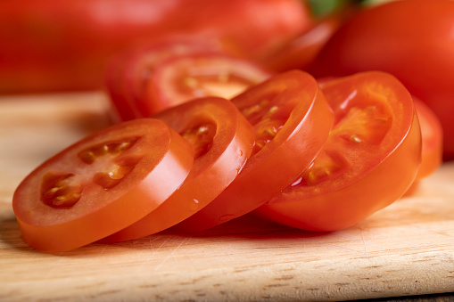 Sliced red fresh tomatoes on a board, cooking salads using tomatoes and cucumbers