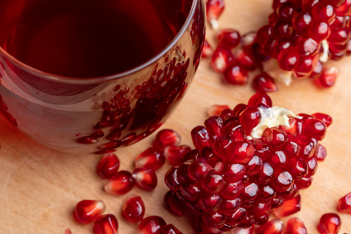 A small ripe red pomegranate is lying on the table, a ripe red pomegranate fruit with large sweet grains