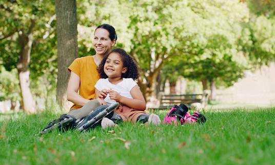 Family, mother and kid in park with rollerblading outdoor, relax on grass and fun in nature with happy people. Woman, girl and taking a break, sports and quality time together with love and care