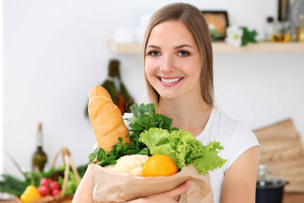 istock Young cheerful smiling woman is ready for cooking in a kitchen. 1487079492