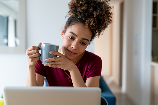 Bautiful African American woman working at home and drinking a cup of coffee