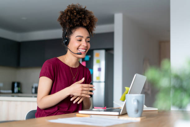 Happy woman working from home as a customer service representative Happy African American woman working from home as a customer service representative and using a headset customer retention stock pictures, royalty-free photos & images