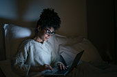 Woman working late at a home in bed and using her laptop
