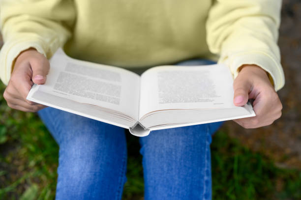istock Woman reading book in park, closeup view 1487081283