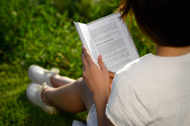 istock Woman reading book outdoors on sunny day, closeup 1487081329