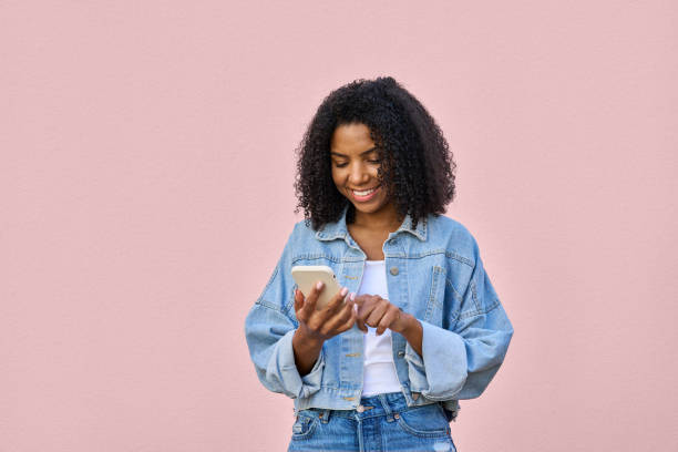 istock A woman using phone in her hand and looking at her phone on pink background 1487082298