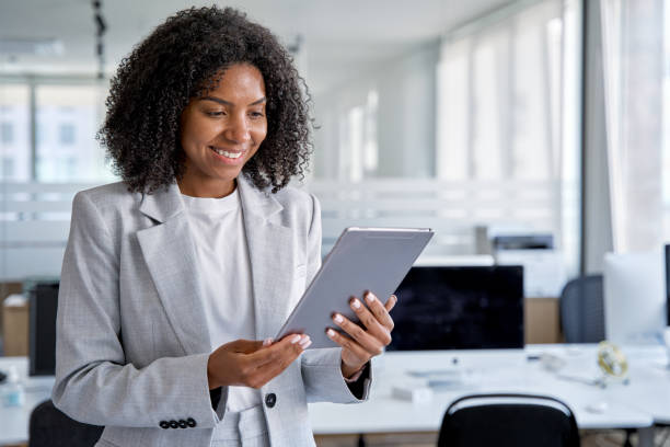 istock Young business woman using touchscreen pc tablet standing in modern office 1487082340