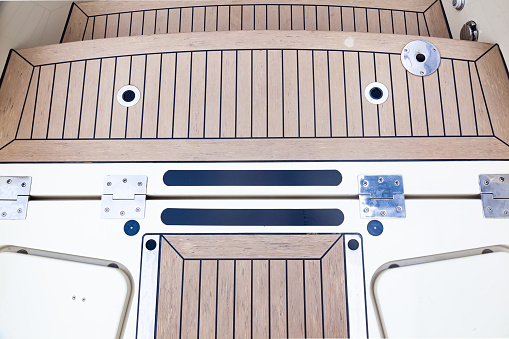 Deck of a luxury modern yacht with closed hatches and steps.