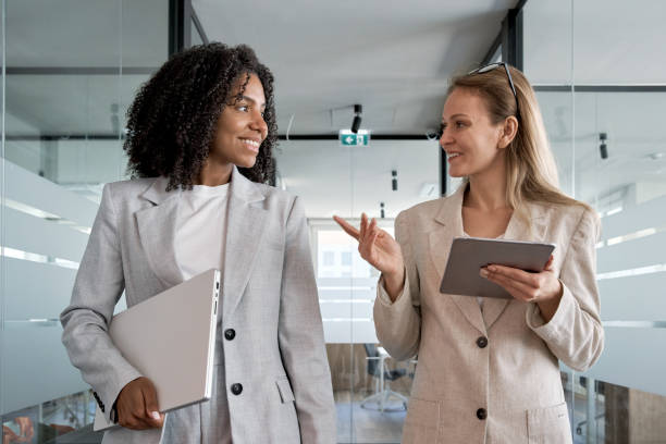 istock Two businesswoman working together, while walking in modern business office 1487085912