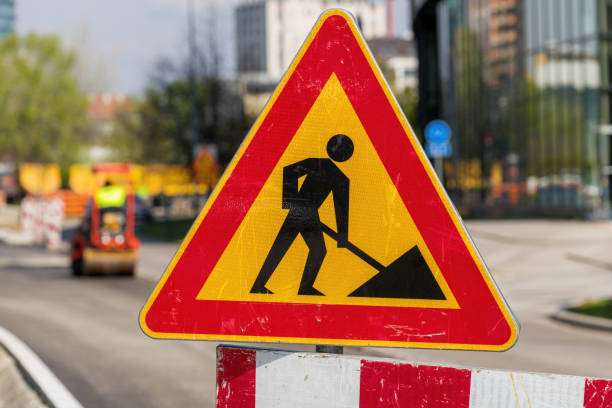 istock Men at work traffic sign at road maintenance project construction site 1487086354