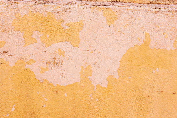 surface rugueuse d’un mur avec peinture écaillée d’un fond texturé de couleur jaune crème pâle - paint rough peeling grunge photos et images de collection