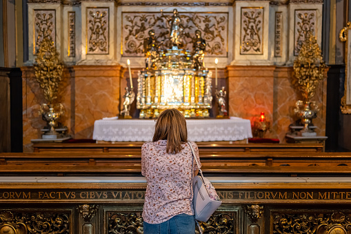 Woman praying in a chapel inside the cathedral basilica del Pilar in Zaragoza, Spain