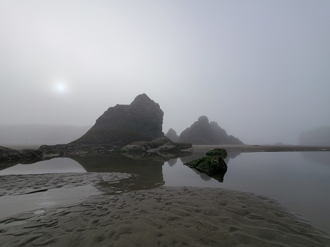 This is a photograph taken on a mobile phone outdoors on a foggy autumn morning of rock formations on Bandon Beach, Oregon.