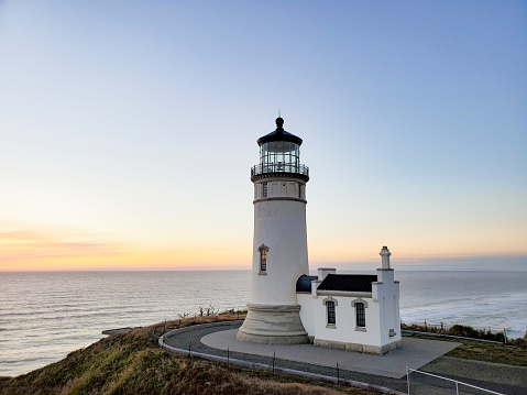 Elevated panorama view of seaside Castle Point Lighthouse on steep cliff hill towering over Tasman Sea Pacific Ocean during sunrise near Wellington, North Island New Zealand