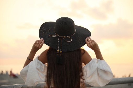 Young woman in hat at sunset, back view