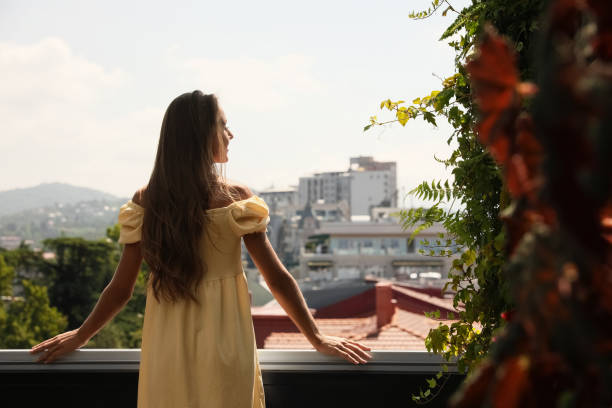 istock Young woman standing on balcony, back view. Space for text 1487091171