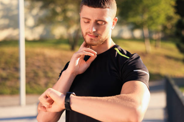 istock Attractive serious man checking pulse after training in park 1487092000