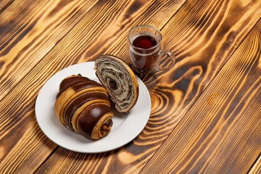 Croissant with chocolate on a wooden background with a cup of coffee