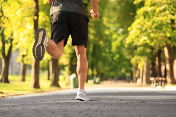 istock Sporty man jogging in park on sunny day, closeup. Space for text 1487093202