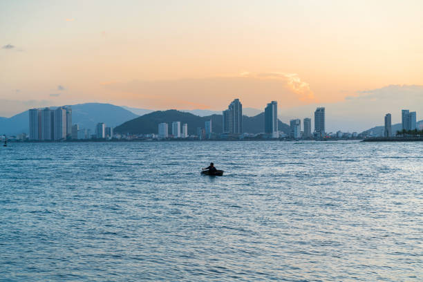Fisherman rowing basket boat on Nha Trang sea in sunset - Nha Trang city, Khanh Hoa province, central Vietnam