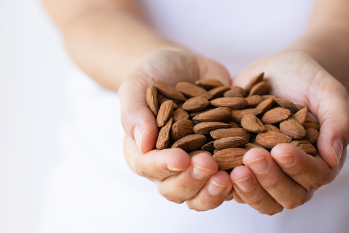 Studio shot of woman showing handful of almonds.