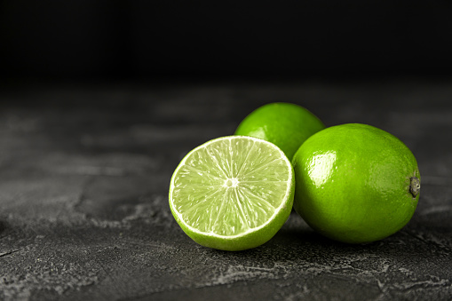 Lime, juicy ripe citrus fruits on a dark background. Ingredients for preparing refreshing drinks and cocktails. Mojito. Selective focus, top view.