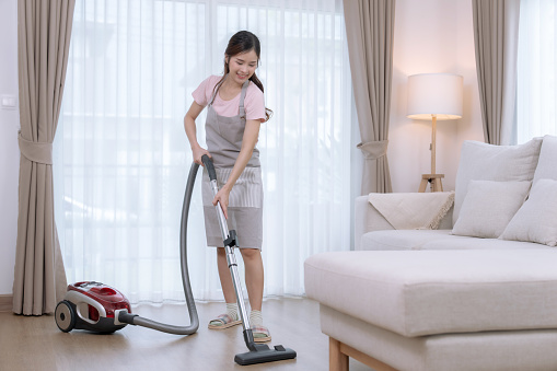 Young Asian woman spending her free time on vacation cleaning the living room at home.