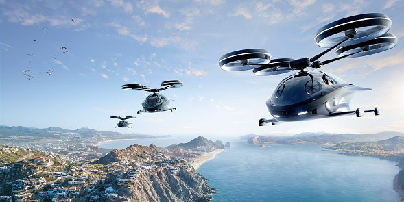 Three generic black eVTOL aircraft flying over a populated coastal location with mountains, beaches in secluded bay on a bright sunny morning. Image taken at altitude.