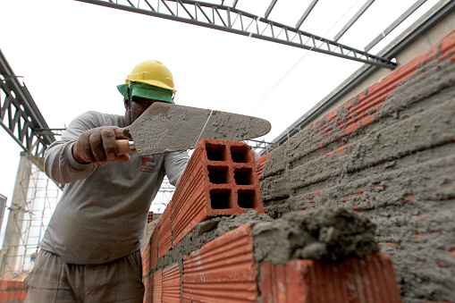 Bricklayer hands with trowel building brick wall