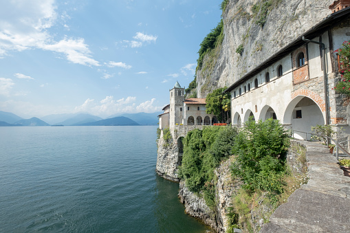 View of the famous Eremo di Santa Caterina del Sasso, Italy Saint Catherine of the stone hermitage. Blue waters of Lake Maggiore on the left. Italian alps and blue sky on the background