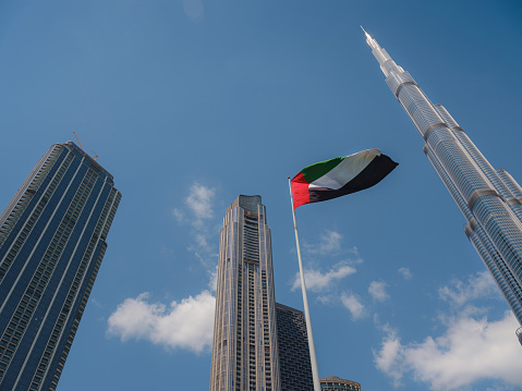 United Arab Emirates flag flying against Dubai downtown skyline. UAE celebrates it's national day on 2nd December every year.