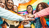 Lgbt group of people stacking hands outside - Diverse happy friends hugging outdoors - Gay pride concept with crowd of guys and girls standing together on city street