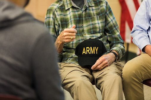 During the support group meeting, an unrecognizable senior adult Vietnam veteran holds his army cap as he talks about his war experience and how it has affected him.