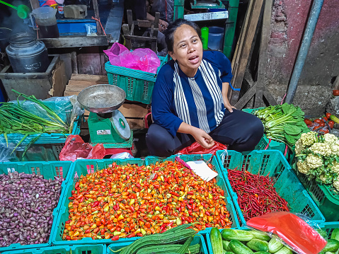 Jakarta, Indonesia - April 10, 2023: Portrait of an Asian woman selling vegetables in front of Pasar Mitra, West Jakarta, Jakarta, Indonesia.