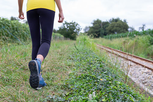 Crop sportswoman strolling near railway tracks during outdoor workout