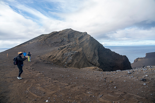 Small group of tourists walking up the Capelinhos volcano on the island Faial, Azores