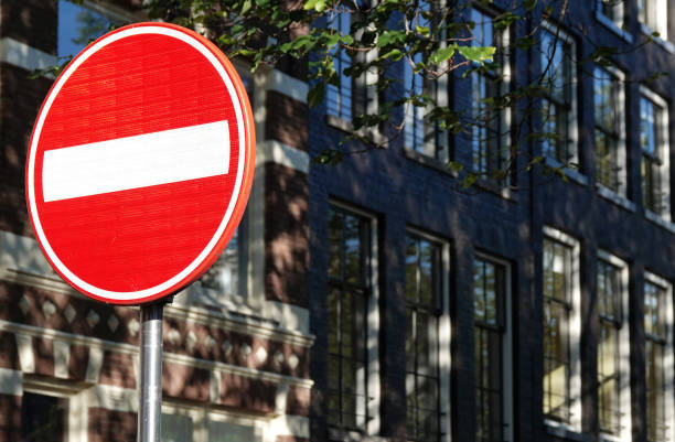 una señal de tráfico de no entrada contra un edificio desenfocado en el fondo. - rules of the road fotografías e imágenes de stock