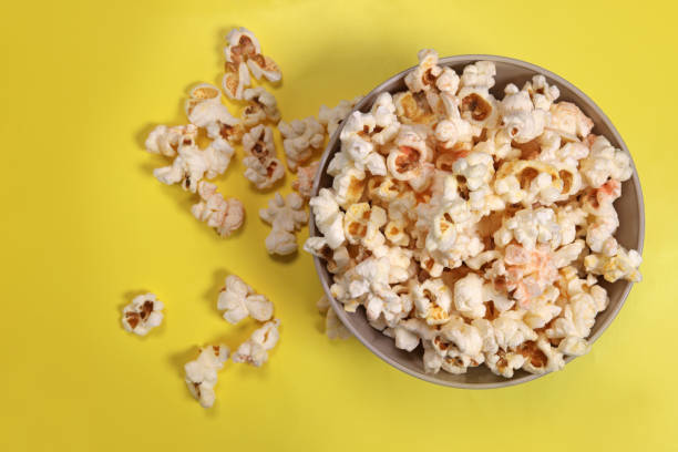 istock Paper cup with popcorn on yellow background, top view 1487117617