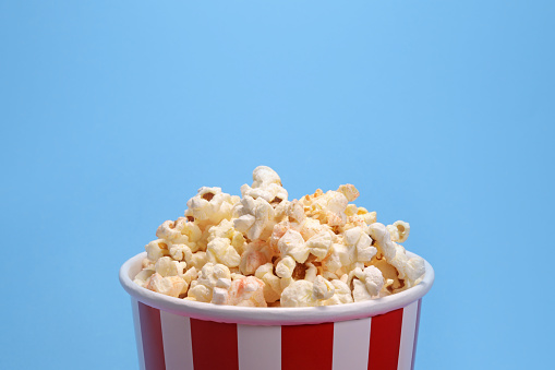 Paper cup with popcorn on blue background. copy space for text