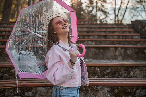 Beautiful woman standing next to a park bench under an umbrella on a rainy day