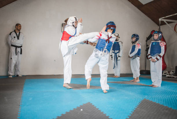 istock Two children practicing taekwondo fighting in a martial arts gym - dojo 1487123656